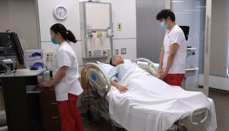 Faculty and a student using an iPad in the simulation lab